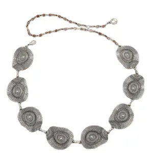 Detail view of the intricate concentric pattern on the metallic silver waist chain medallion.