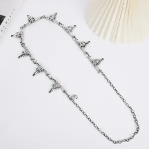Close-up detail of vintage western metal waist chain with bull skull pendants and turquoise.