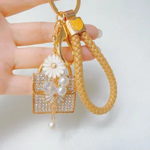 Creative rhinestone daisy handbag keychain with braided leather strap and pearl charms.