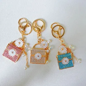 Close up detail view of cute rhinestone daisy handbag keychain with pearls and metal finish.