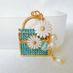 Closeup of a cute mini rhinestone daisy handbag keychain pendant with pearls and tassel detail.
