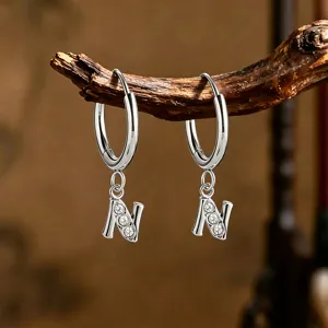 Pendientes de aro huggie de acero inoxidable plateado letra N con dijes de cristal brillante.