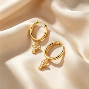Primer plano de pendientes de aro minimalistas de oro 18K letra Y con circonitas brillantes.