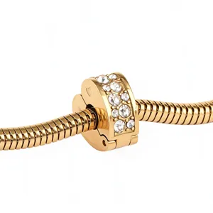 Close-up detail of gold stainless steel snake chain bracelet charm with sparkling cubic zirconia.