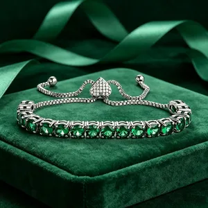 Nahaufnahme des grünen Zirkon Tennisarmbandes mit verstellbarem Herzschieber auf grünem Samt.