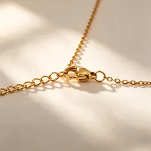 Detailed view of the gold tone metal necklace lobster clasp and extension chain, elegant design.