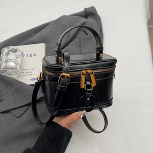 Sac à main vanity en cuir verni noir classique avec poignée supérieure et matériel doré chic.