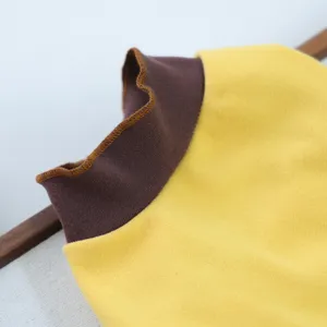 Detail view of a yellow pet shirt with brown rolled collar for small dogs in spring autumn.