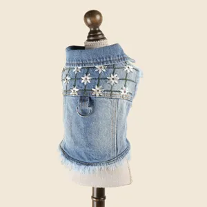 Close-up detail of stylish denim pet jacket featuring cute daisy embroidery and metal leash ring.