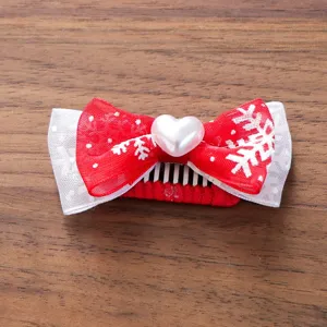 Detailaufnahme der Weihnachts-Haarspange für Haustiere mit roter Schleife und Herzperle.