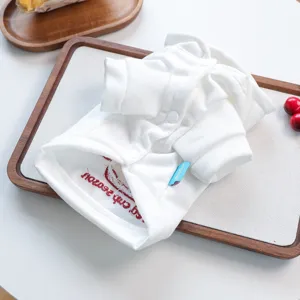 Detailed view of a white small dog hoodie, folded neatly on a wooden tray with cute embroidery.