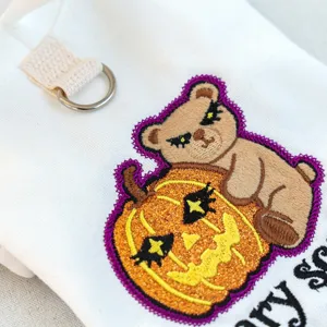 Détail de sweat pour animal Halloween avec broderie mignonne d'ours et citrouille.