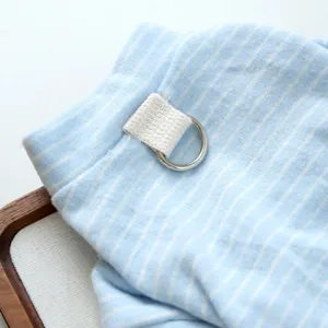 Close-up detail of soft blue striped pet clothing with metal D-ring and fabric loop.