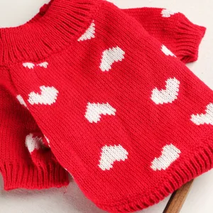 Red knit pet sweater closeup showing soft yarn and cute white heart patterns for small dogs.