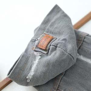 Close-up detail of grey pet denim jacket showing retro ripped texture and stitched brand label.