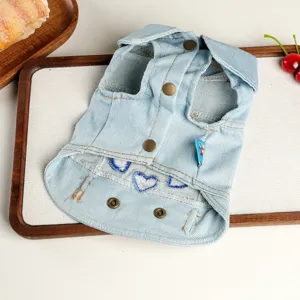 Close-up detail of blue denim pet vest featuring cute heart embroidery and metal snap buttons.