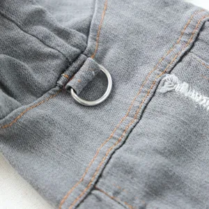 Grey pet denim jacket detail featuring orange stitching, metal D-ring and distressed texture.