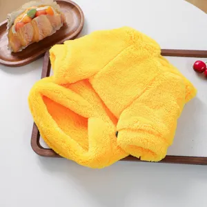 Detail view of the soft yellow plush pet costume folded neatly on a wooden tray.