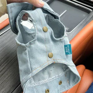 Close-up detail of denim pet vest showing durable fabric, metal buttons, and stitching.