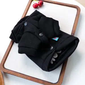 Vue détaillée d'un sweat à capuche élégant noir pour chien avec boutons et étiquette.