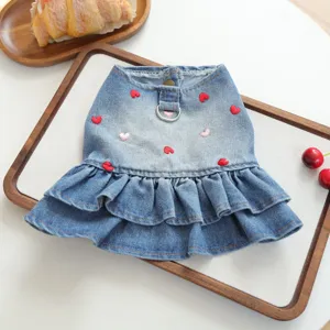 Close-up detail of cute denim pet dress with red heart embroidery and ruffled hem.