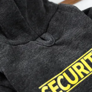 Detailed view of pet hoodie, dark grey fabric with yellow security print and hood.