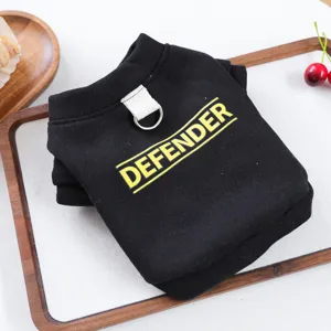 Primer plano de una sudadera negra para mascotas con estampado amarillo defender y anilla.