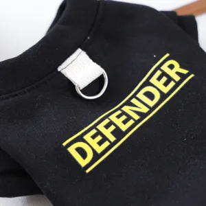 Detalle de sudadera negra para perros con anilla en D e impresión de letras amarillas.