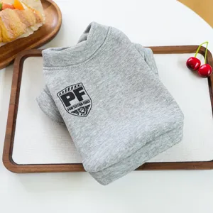 Detalle sudadera gris para mascota, ropa suave para perro con logo de escudo para otoño invierno.