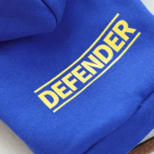 Blue pet hoodie detail shot featuring bold yellow DEFENDER letter print for small dogs.