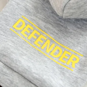Grey pet hoodie detail with yellow defender print for small dogs, comfortable cotton fabric.
