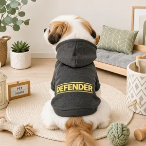 Detailed view of grey pet dog hoodie with yellow defender text print in cozy room lifestyle.