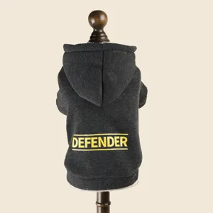 Detail shot of a dark grey pet hoodie with yellow Defender text print on the back, small dog.