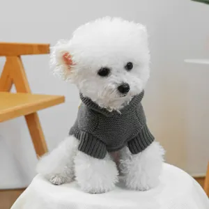 Closeup of a cute puppy wearing a cozy dark gray knitted turtleneck sweater indoors.