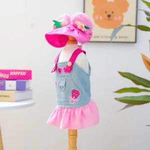 Detailed view of cute pet denim overall skirt and pink plush strawberry hat, fine stitching.
