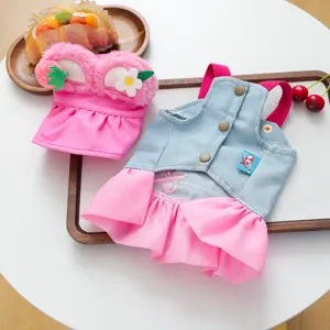 Pet clothing detail view showing cute pink plush strawberry hat and blue denim dress set.