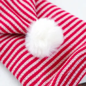 Close-up detail of red and white striped pet hoodie with fluffy white pom-pom decoration.