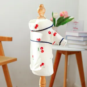 Cute cherry print pet pajama detail shot, soft white fabric with blue trim, cozy home aesthetic.