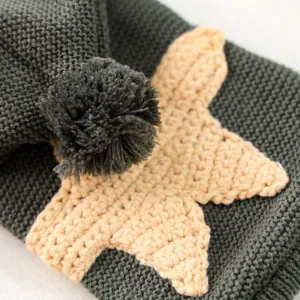 Close-up detail of grey knit pet sweater featuring starfish applique and soft pom-pom.