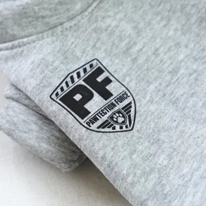 Vista detallada de tela gris de sudadera para mascota con estampado de escudo.