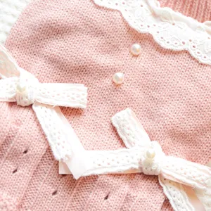 Gros plan détaillé d'une jolie robe tricotée rose pour animal avec dentelle et perles.