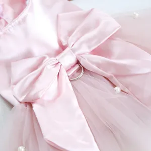 Gros plan sur la robe rose pour animal, nœud en satin, tulle, perles, vêtement pour chat.