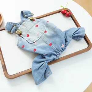 Detail shot of cute pet denim jumpsuit with heart embroidery and metal buckles on tray.