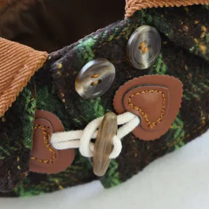 Primo piano del mantello invernale per animali con tessuto scozzese verde e chiusura ad anello.