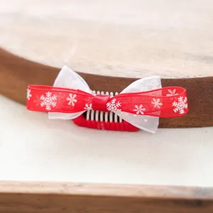 Nahaufnahme eines süßen Weihnachtsschneeflocken-Haarclips für Haustiere mit roter Schleife.