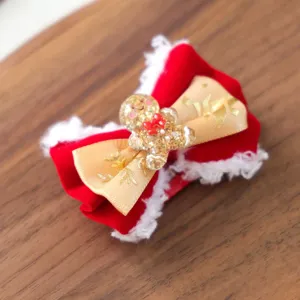 Weihnachtliche Haarklammer für Haustiere mit rotem Samt und goldenem Lebkuchenmann-Design.
