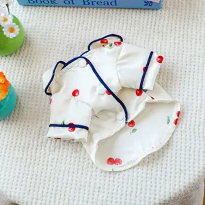 Detailed view of pet cherry print pajama, cream silk fabric with blue piping and cute buttons.