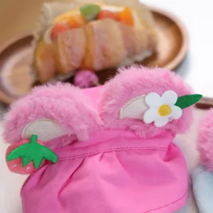 Close-up detail of cute pink plush pet hat with sweet strawberry and flower decoration.