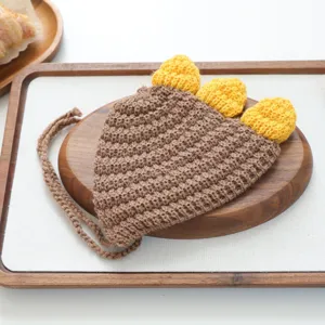 Gros plan détaillé du joli chapeau de compagnie au crochet dinosaure marron avec épines jaunes.