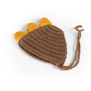 Vue de detail rapprochee du bonnet tricot dinosaur marron pour animaux avec picots jaunes.